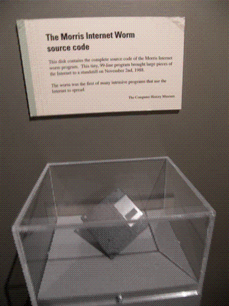 A floppy disk holding the Morris worm source code, displayed in a museum case beneath a placard reading 'The Morris Internet Worm source code'