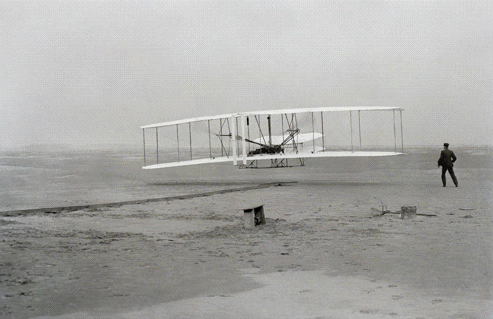 The Wright Flyer lifting off at Kill Devil Hills on December 17, 1903, Orville at the controls and Wilbur running alongside