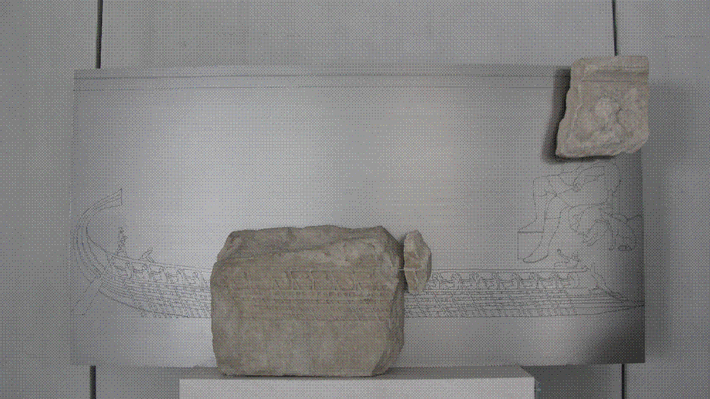 Weathered marble relief fragment carved with the flank of an Athenian trireme, showing three staggered banks of nude rowers bending over their oars beneath the ship's deck rail.