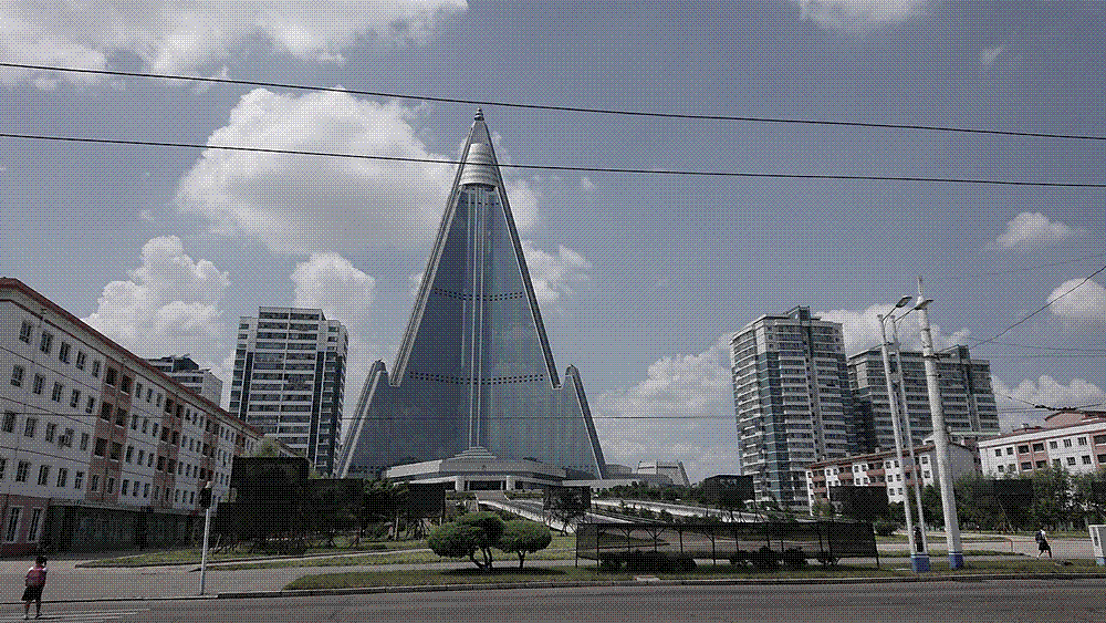 The glass-clad pyramid of the unopened Ryugyong Hotel towering over the rooftops of Pyongyang