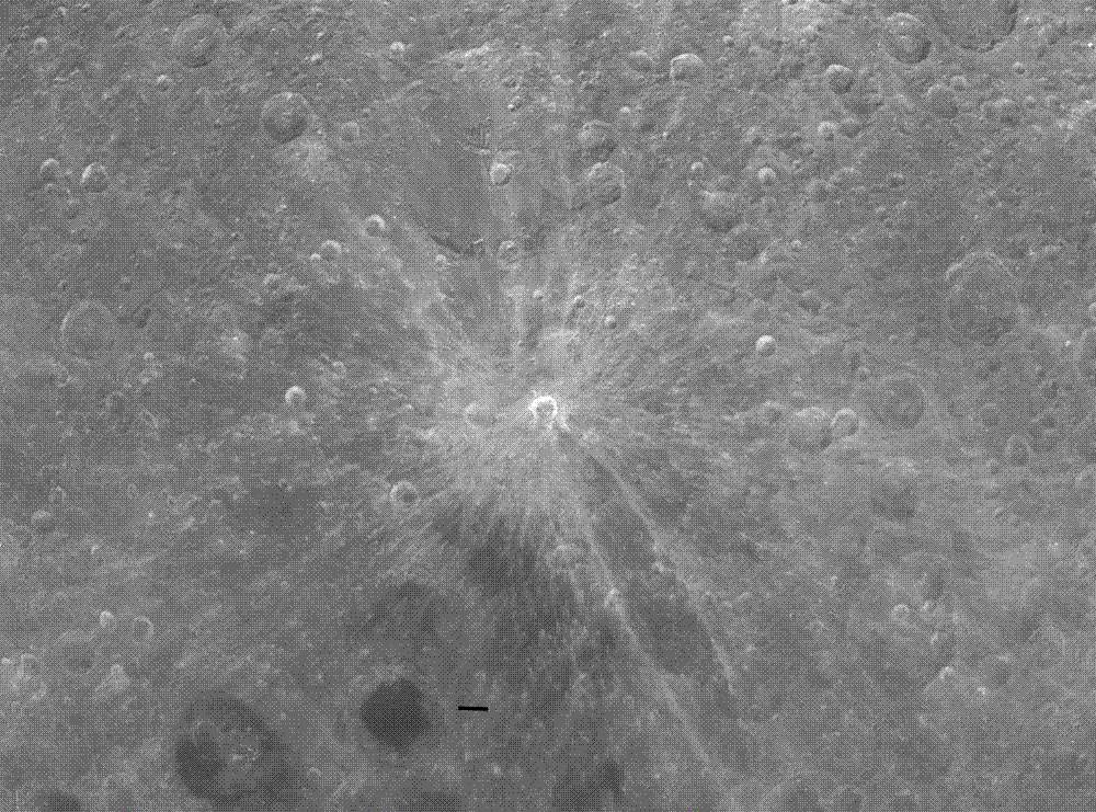 Grey, heavily cratered lunar terrain photographed from orbit, with one small brilliant white crater at the centre throwing long pale rays outward across the older, softened ground.
