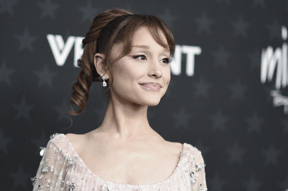 Ariana Grande photographed on a red carpet in a pale embellished gown, looking away from the cameras.