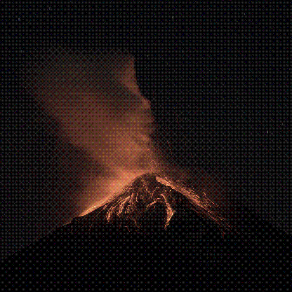 The Volcan de Fuego in Guatemala erupting at night, incandescent rock streaming down its flanks beneath a glowing ash plume.