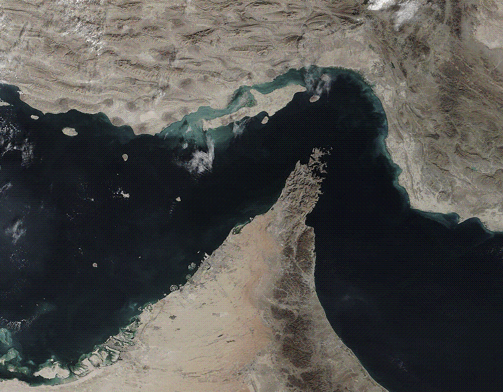 Satellite view of the Strait of Hormuz between the Musandam Peninsula and the Iranian coast, dark blue water between tan desert landmasses