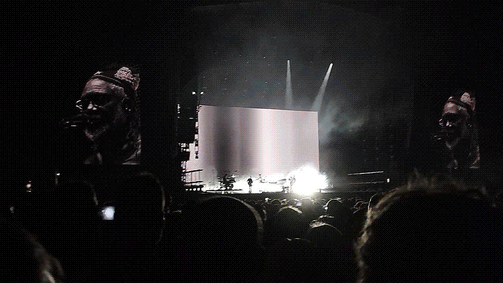 A concert stage lit in blue with a crowd silhouetted in front, illustrating a live music performance.