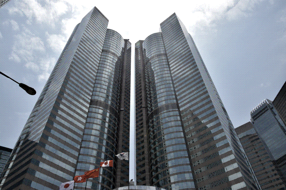 The pale granite towers of Exchange Square in Central, Hong Kong, home of the Hong Kong Stock Exchange, seen from the street below.