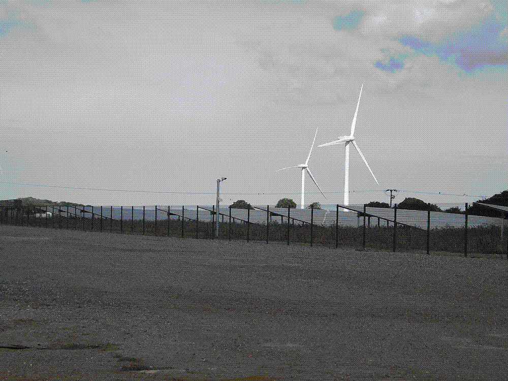 Onshore wind turbines and solar panels in a European countryside.