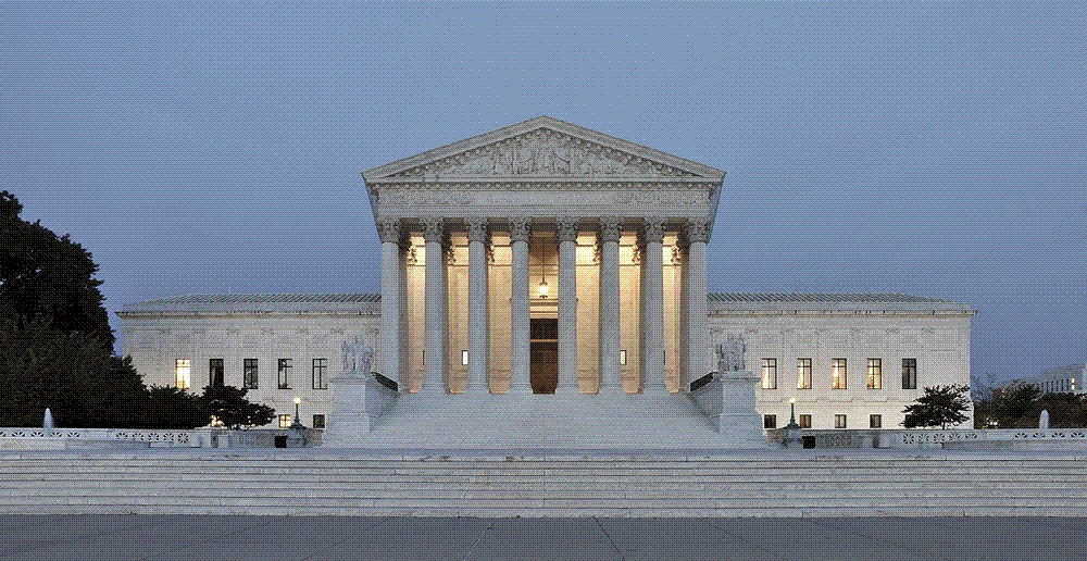 The marble west facade of the United States Supreme Court building with its tall Corinthian columns, photographed at dusk.